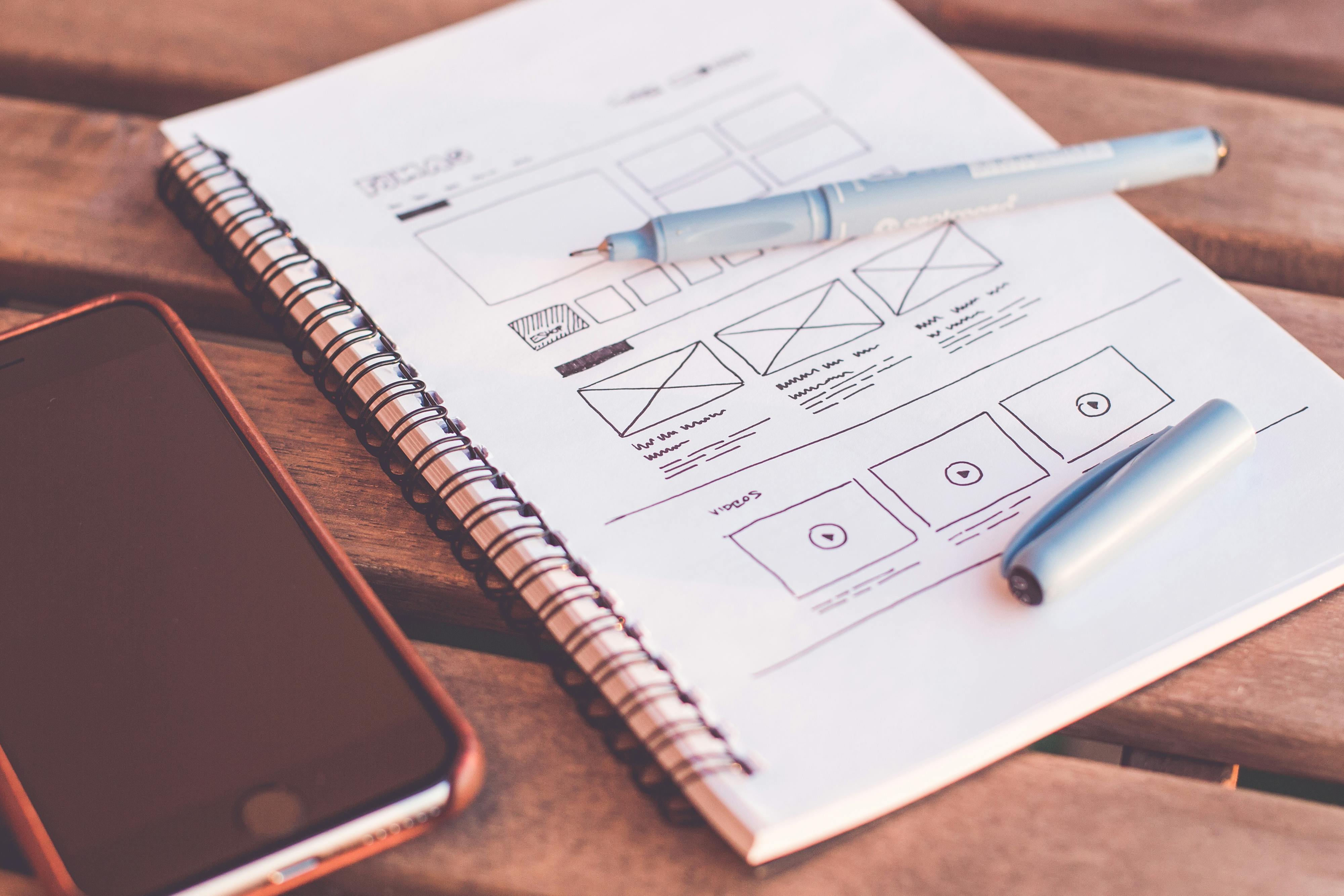 Notebook and phone on a desk beside planning notes